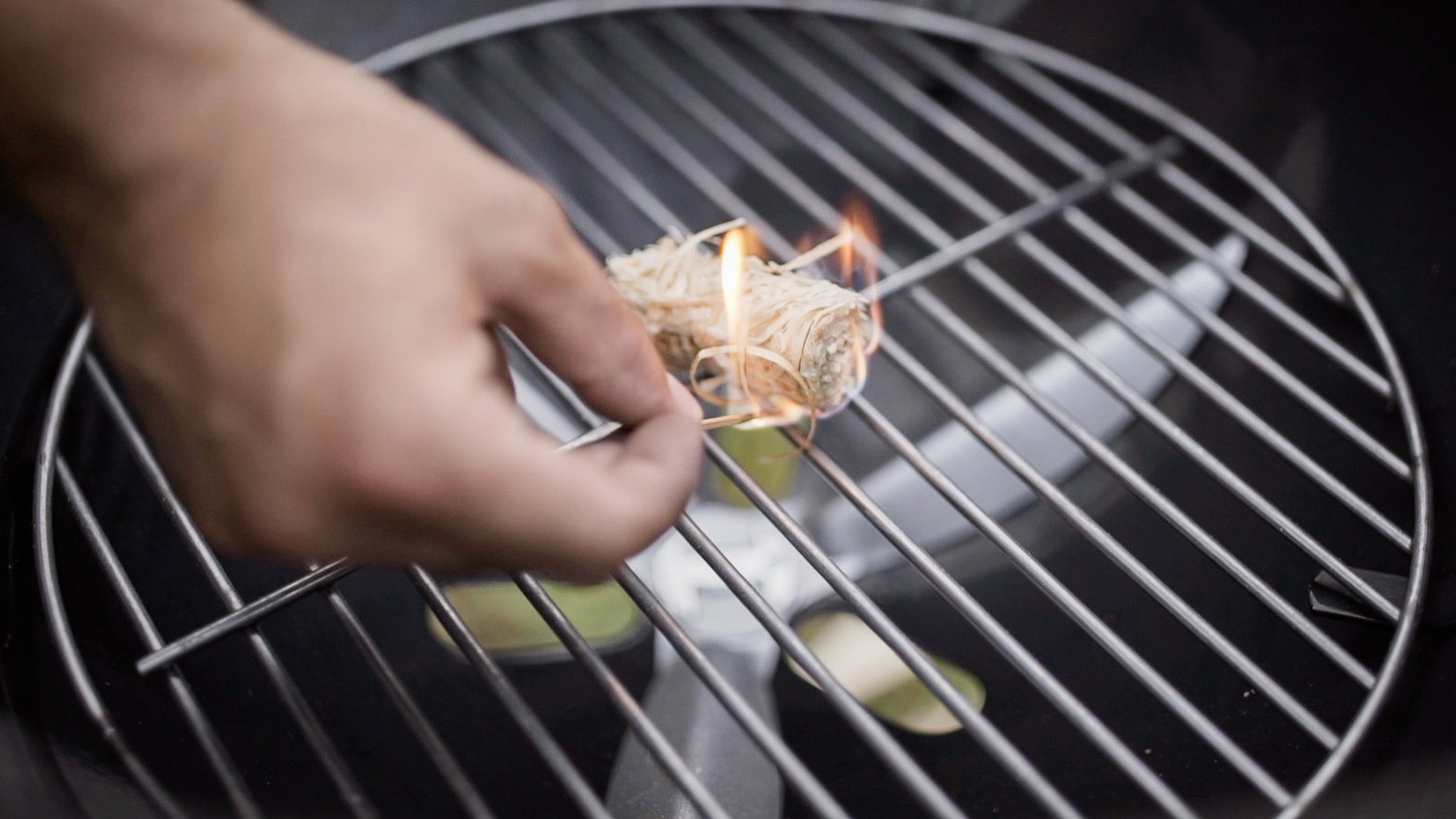 Optændingsuld på grillrist Hånd tænder optændingsuld på metalgrill