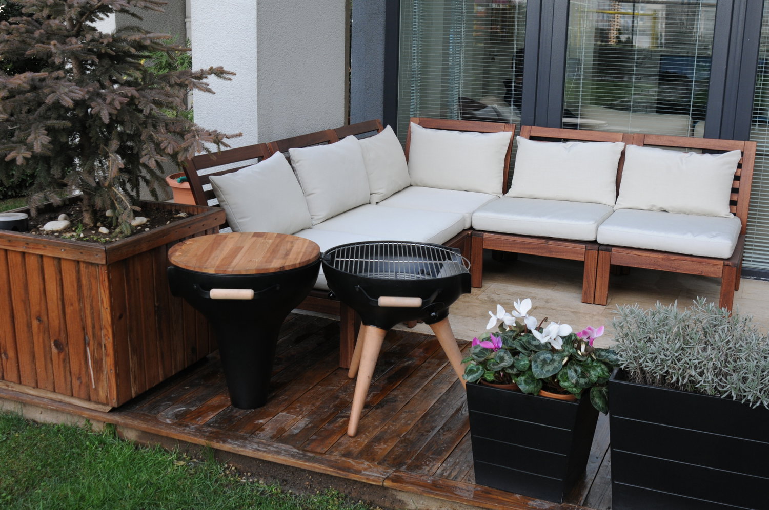 Terrasse med træsofa, grill og plantekasser