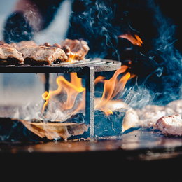Kød steges på varm udendørs grill med flammer