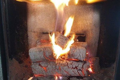 Brændeovn med brændende træstammer, glødende kul og klare, varme flammer