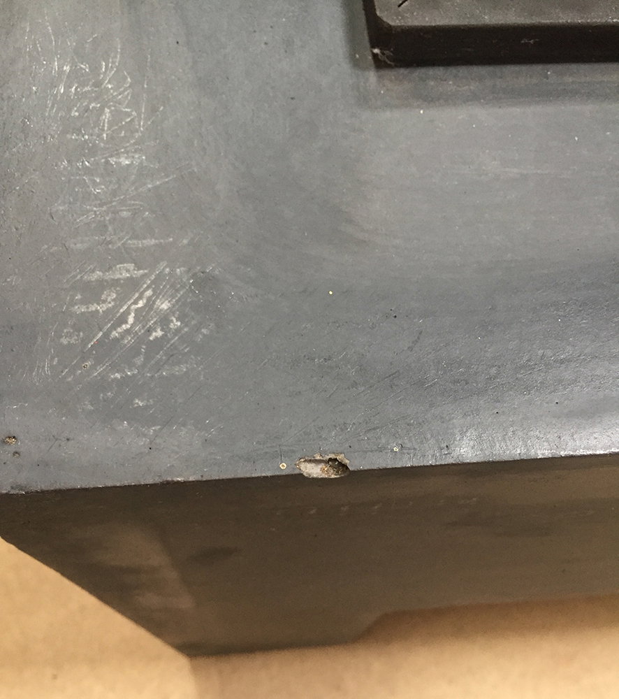 Nærbillede af grå metaloverflade med kantafslag
