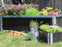 Sort højbed i træ fyldt med blomster og grøntsager i have