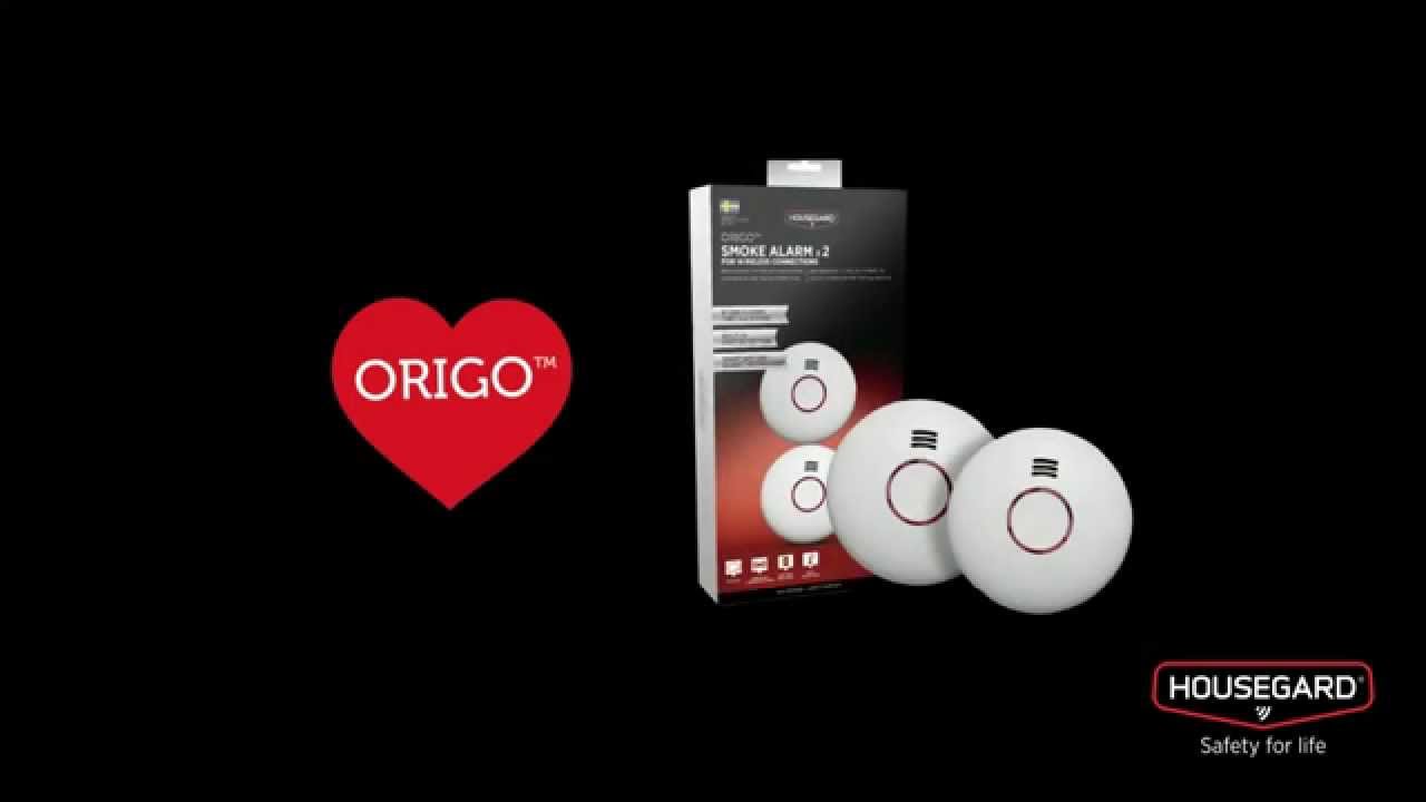 Produktbillede af Origo serieforbundne varme- og røgalarmer (2 stk) fra Housegard vist med emballage og Origo hjertelogo på sort baggrund – sæt med trådløst sammenkoblingssystem (op til 30 alarmer) og lang batterilevetid (op til 18 måneder, 2×AA).
